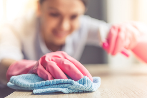 Žena si při úklidu chrání ruce gumovými rukavicemi, aby ji na pokožce nevznikly praskliny.